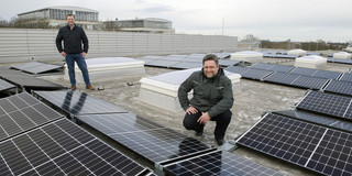 Two men on a roof with photovoltaic panels