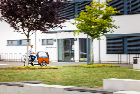 Ein Mann fährt auf einem Lastenrad vor dem Gebäude der Emil-Figge-Str. 38a.