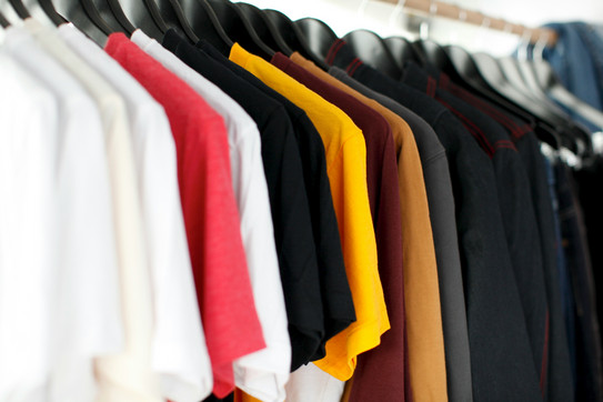 You can see different colored T-shirts on a clothes rail