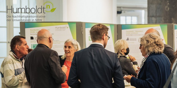 Diskussionrunde vor einer Posterwand. Darüber das Logo von HumboldtN