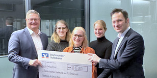 Drei Studentinnen bekommen von zwei Vorständen der Dortmunder Volksbank einen Spendenscheck überreicht.