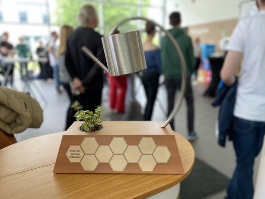 Cup in the shape of a watering can with a small plant underneath