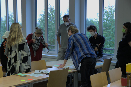 Gruppe steht am Tisch zusammen 