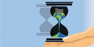 Earth trickles through an hourglass held in a hand.
