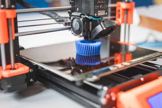 The picture shows a 3D printer in operation. 
