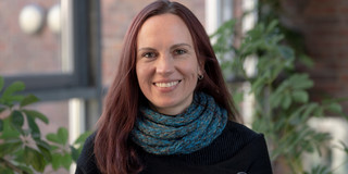 Kerstin Guhlemann Porträt Bild von einer Frau vor einem Fenster, diese Frau ist Kerstin Guhlemann.
