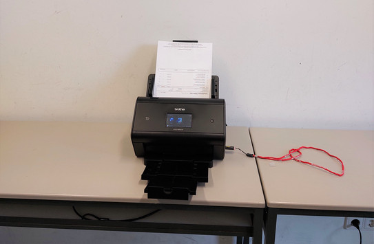 A scanner with usb-stick and paper stands on a table. 
