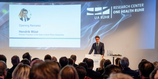 Foto: Ministerpräsident Hendrik Wüst steht an einem Redepult bei der Eröffnung des Research Centers One Health Ruhr. Vor ihm sitzen Menschen im Publikum.