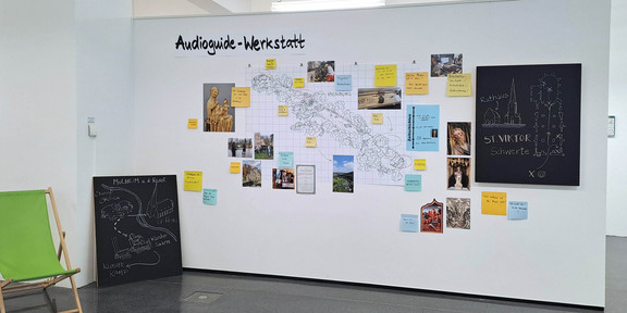Route Mittelalter Ruhr_Exhibition A map, photos and colorful pieces of paper with information hang on a wall