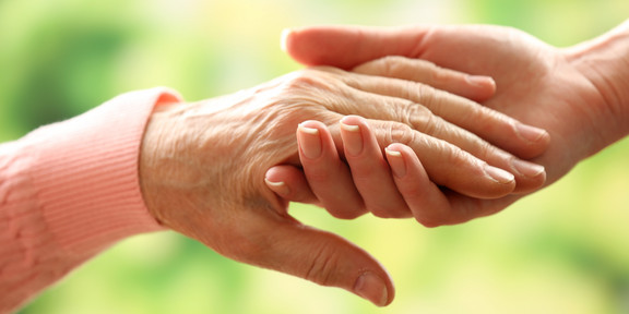 One hand holds another: The right hand looks young, the left hand has wrinkles and looks old.