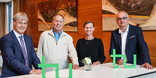 Gambrinus-Forum Prof. Quante, Prof. Barzilai, Frau Prof. Flatten und Rektor Prof. Bayer stehen gemeinsam an einem Tisch, auf dem das TU-Logo steht.