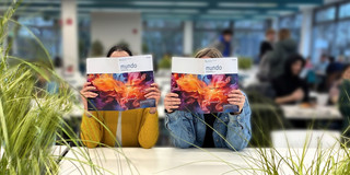 Photo: Two people sit at a table and show the magazine “mundo”.