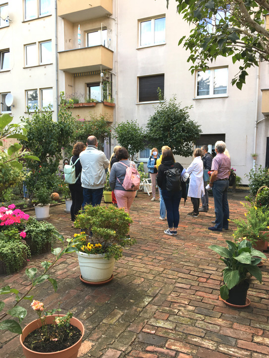 The picture shows a group of people in a planted backyard.