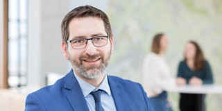 Ein Foto von einem Mann mit Brille im blauen Anzug