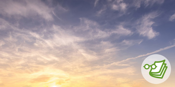 A blue sky with white clouds and yellowish tint from the sun.