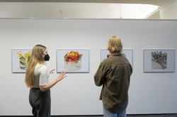 Zwei Besucher*innen betrachten eine Serie aus Kunstwerken
