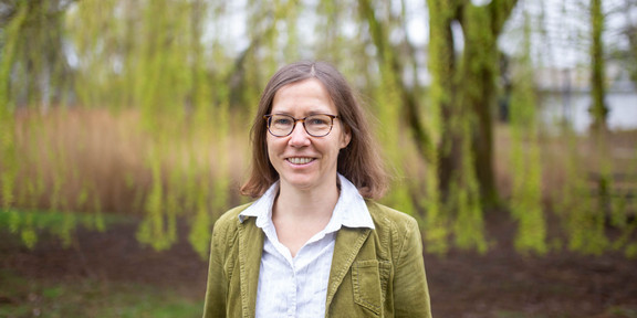 Ein Porträtfoto von einer Frau mit Brille und weißer Bluse auf dem Campus der TU Dortmund.