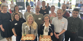 Zu sehen ist eine Gruppe von Mitarbeitenden der TU Dortmund und der FH Dortmund. Im Vordergrund stehen die Preisträgerinnen des "Impact Cups", ein Nachhaltigkeitspreis. Die Preisträgerinnen halten ihren "Pokal" in den Händen. 