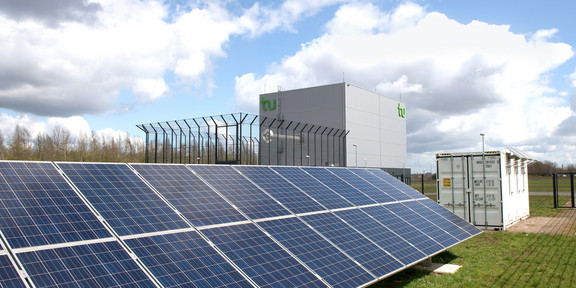 Photovoltaic system on green lawn with clouds in the sky.