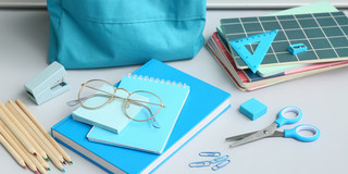 Brille, die auf blauen Schulmaterialien liegt