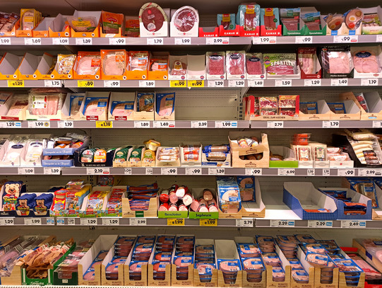 A supermarket shelf filled with food, especially sausages.