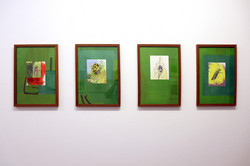 Das Foto zeigt vier grüne Bilder mit unterschiedlichen Motiven nebeneinander in braunen Bilderrahmen an einer weißen Wand hängend.