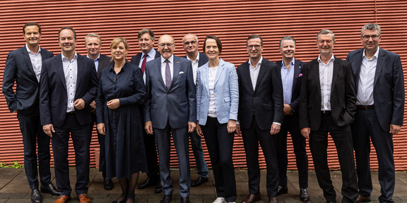 Gruppenfoto vor einer orangenen Wand.