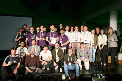 Gruppenfoto: Eine Gruppe von Personen steht gemeinsam auf einer Bühne bei einer Veranstaltung und posiert für ein Foto.