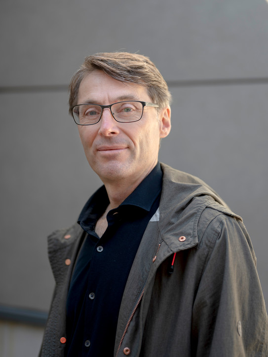 Ein Porträtbild von einem Mann, Prof. Zimmermann auf grauem Hintergrund.