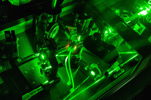 Eine Detailaufnahme eines Lasers im Labor in dunkel grünen Farben.