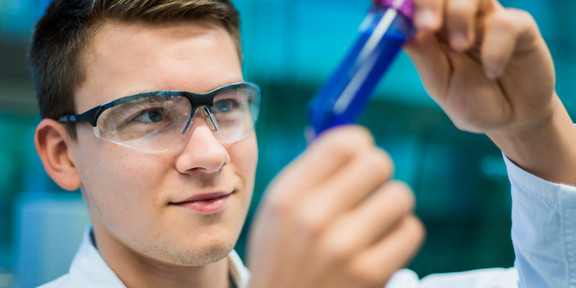 Forschende mit Probengefäß Eine forschende Person hält ein Probengefäß in der Hand.