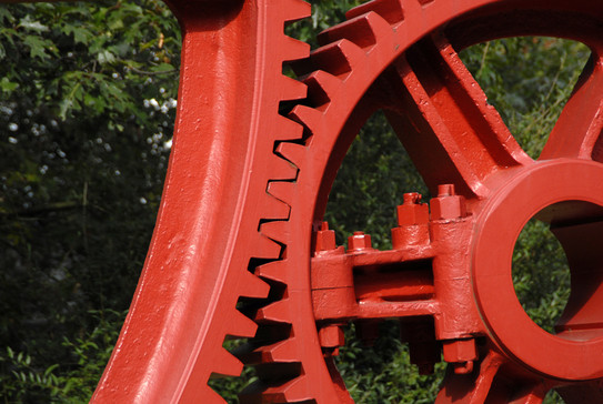 The teeth of two large red steel gears get caught.