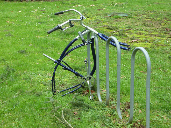 A stolen bicycle with only one handlebar is connected on green lawn.