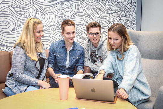 Group of students with a laptop in armchairs A group of four people looking on the screen of a laptop