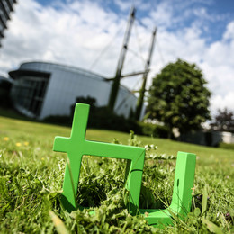 Nachhaltigkeitsstrategie Im Vordergrund steht das TU-Logo im Gras, im Hintergrund das Audimax.
