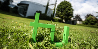 In the foreground one can see the green TU logo on the grass and in the background there is the Mathetower.