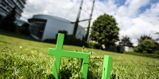 In the foreground one can see the green TU logo on the grass and in the background there is the Mathetower.