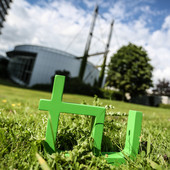 Im Vordergrund steht das TU-Logo im Gras, im Hintergrund das Audimax.