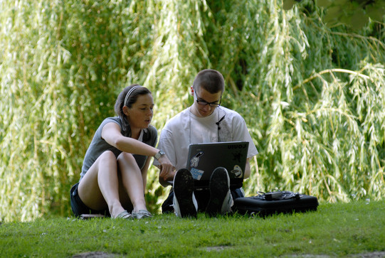 Studierende beim Lernen auf der Wiese Eine Studentin und ein Student beim gemeinsamen Lernen mit Laptop auf einer Wiese im Sommer