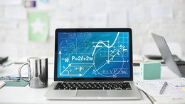 Ein Laptop mit mathematischen Formeln steht auf einem weißen Schreibtisch neben einer Tasse, Stiften und Blättern.