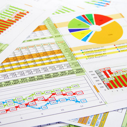 Facts and Data Paper pages with tables, pie charts, column charts as well as graph charts lie on top of each other.