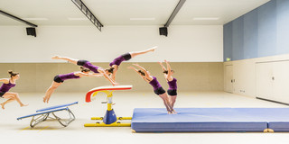A motion study of a woman jumping over a gymnastic apparatus.