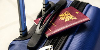 Auf einem blauen Koffer liegt ein Reisepass.